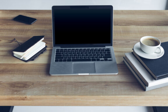 Close-up view of open laptop with blank screen and cup of coffee at workplace