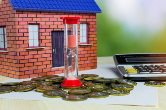 Hourglass house money and calculator on the table. The concept of time